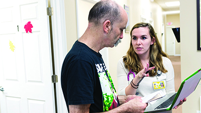 U-M School of Nursing student holds a clipboard while talking to a patient