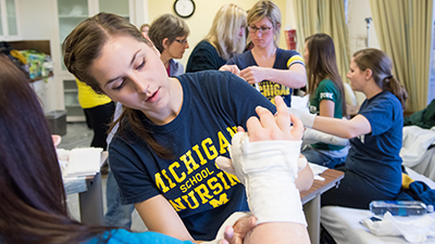 Nursing student in tshirt wraps a cast around an arm