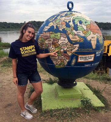 Student points to Africa on a globe while she's in Uganda. 